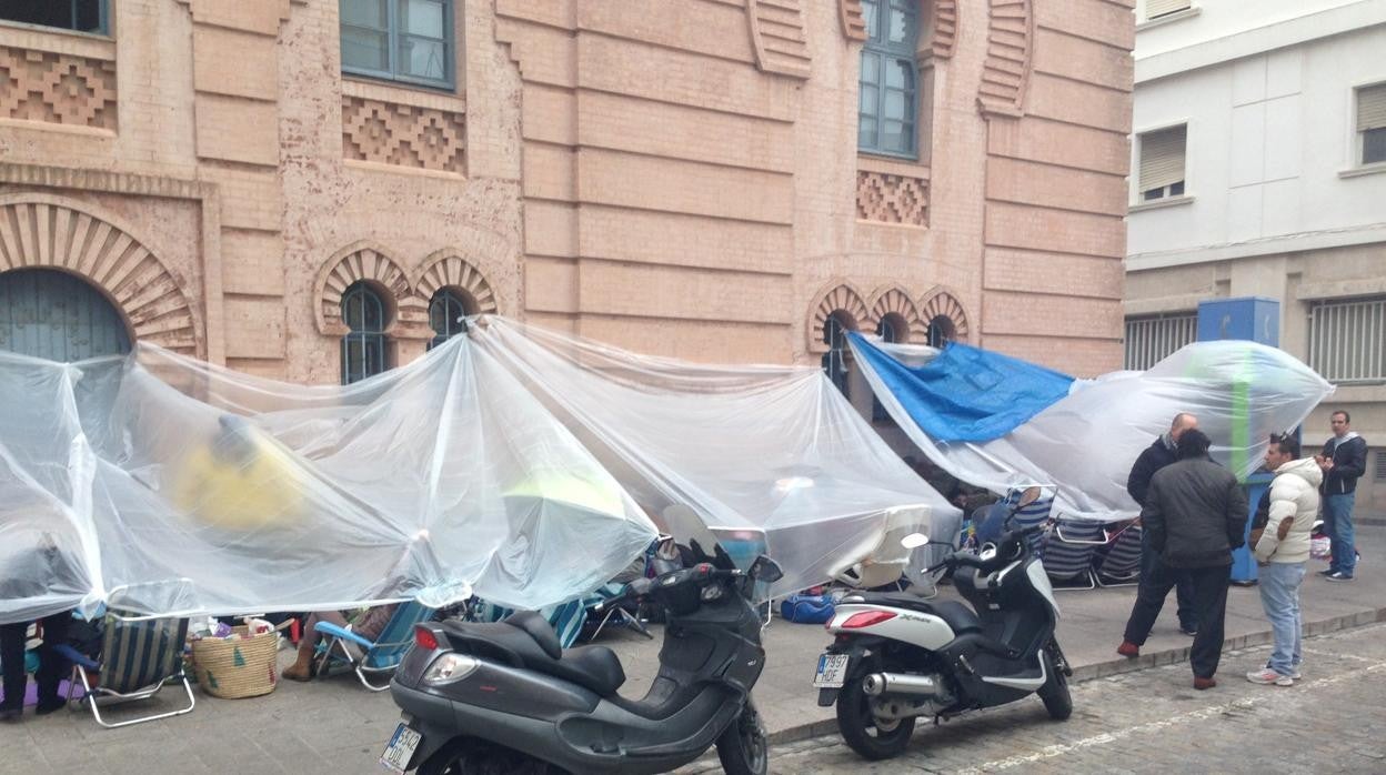 Aficionados hacen cola para el Concurso de Carnaval bajo toldos y lluvia en 2013 junto al Gran Teatro Falla.