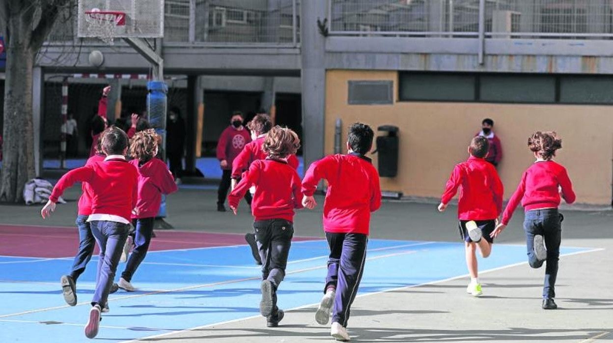 Varios alumnos corriendo en el patio de un colegio.