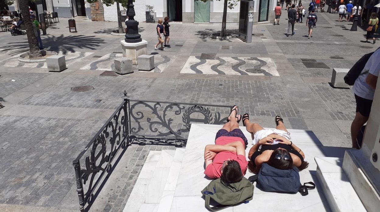 Dos turistas toman el sol en el edificio de Moret, en la Plaza de San Juan de Dios de Cádiz capital.