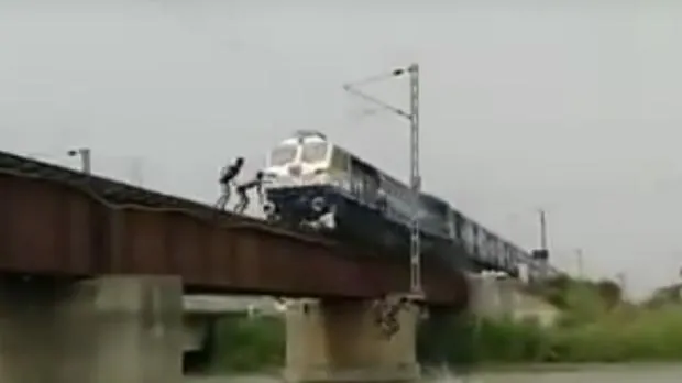 Varios niños saltan desde la vía del tren en el momento que pasa un tren