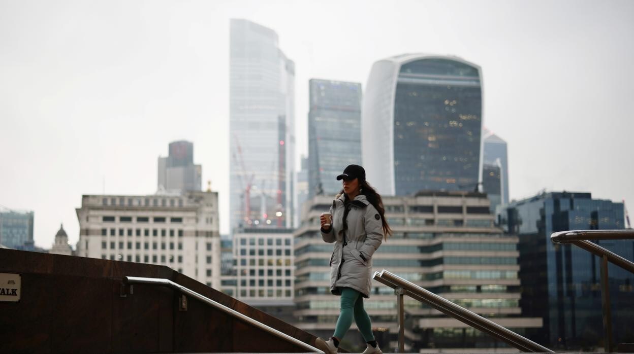 El distrito financiero de la ciudad de Londres se puede ver como una mujer camina por un sendero a lo largo del río Támesis