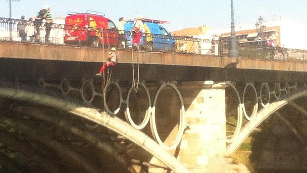 Dos operarios de una empresa de trabajos verticales, colgados del puente de Triana ayer