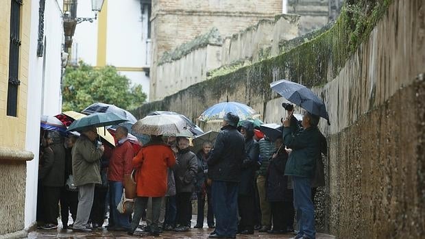 Turistas sevillanos se protegen de la lluvia con paraguas en el Callejón del Agua