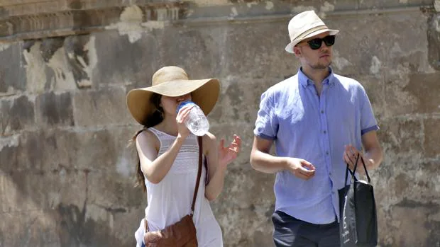Unos turistas se refrescan mientras pasean por las calles de Sevilla