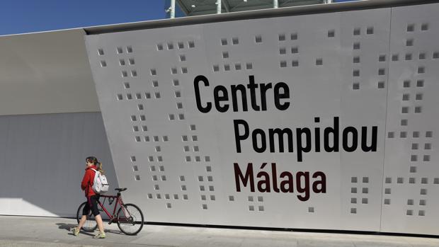 Una joven ciclista pasa junto a la fachada del Centre Pompidou de Málaga