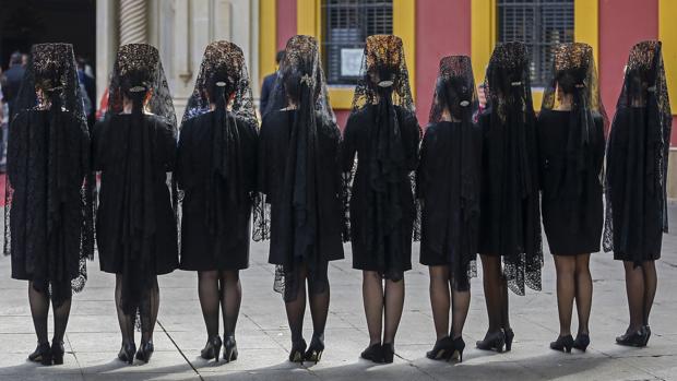 Un grupo de sevillanas vestidas de mantilla este Jueves Santo en la plaza de San Lorenzo