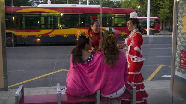 Un grupo de jóvenes ataviadas con el traje de flamenca esperan el autobús