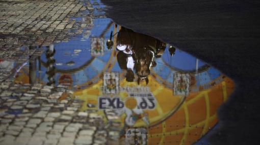 Reflejo de la portada y un caballista en un charco