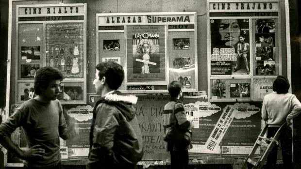 Varios jóvenes consultan carteleras en una imagen de 1978