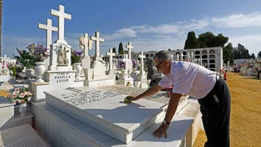 Un hombre acondiciona una lápida en el cementerio de Sevilla