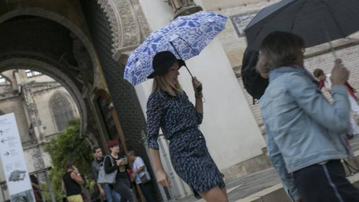 Una joven se protege de la lluvia en el entorno de la Catedral