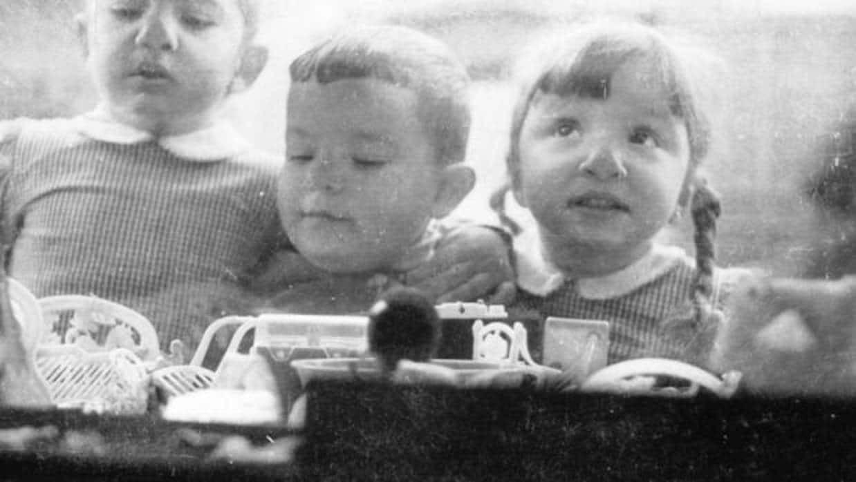 Tres niños contemplan con entusiasmo el escaparate de una juguetería de Sevilla