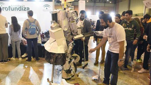 un joven manipula un robot en presencia de unos escolares