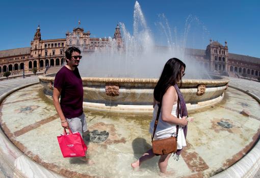 Dos jóvenes se refrescan en la fuente de la Plaza de España