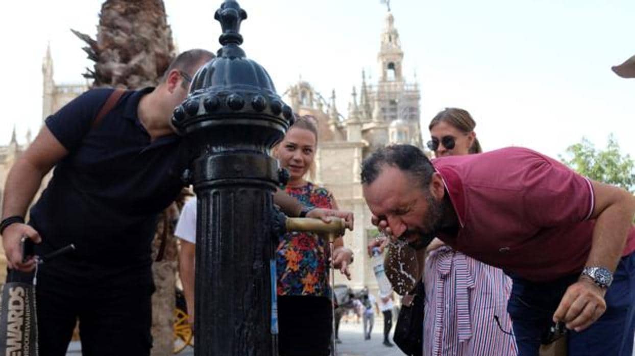 Una joven se refresca en una fuente en plena ola de calor en Sevilla