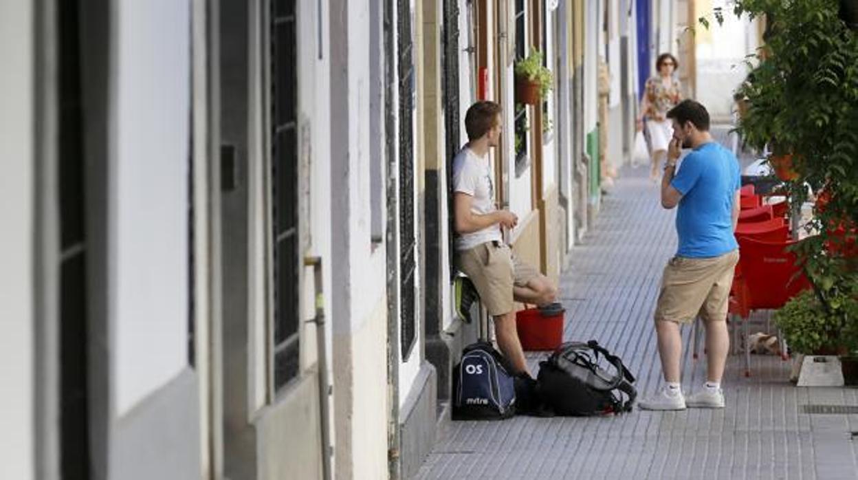 Unos turistas con sus maletas en una calle sevillana