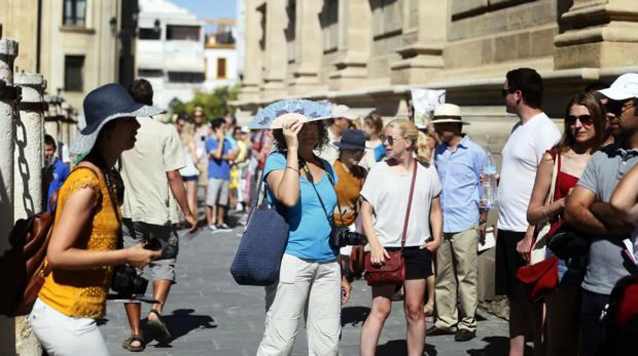 Algunos turistas intenta refugiarse del sol en el centro de Sevilla
