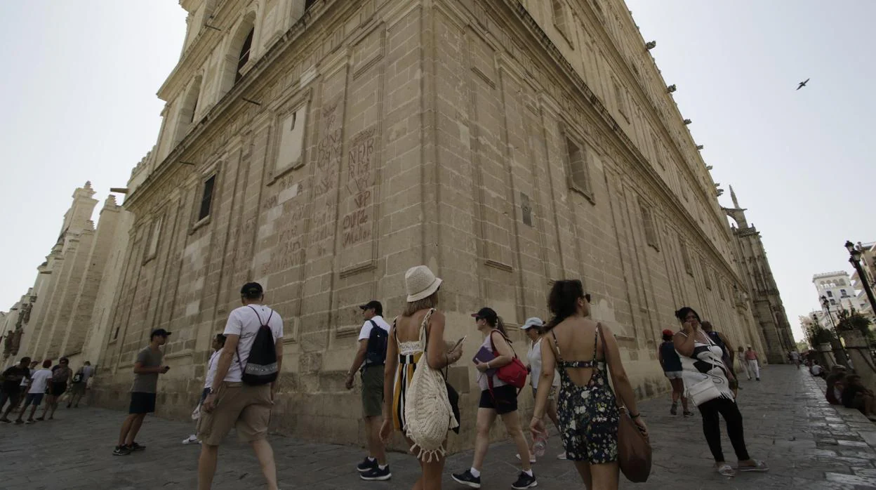 Turistas pasean junto a la sevillana iglesia del Sagrario