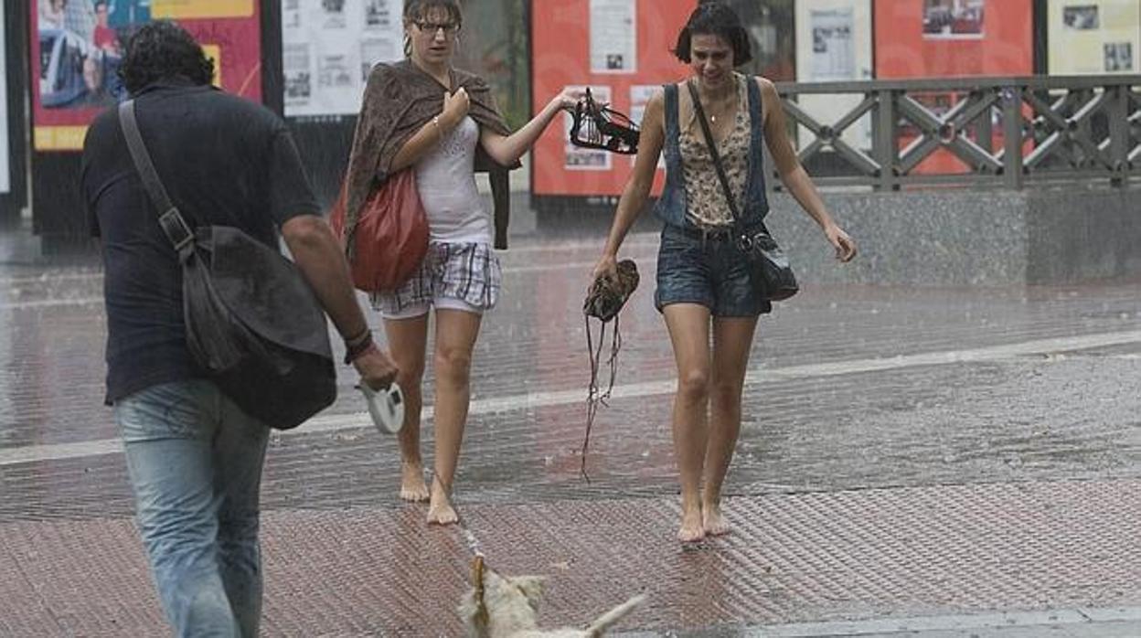 Varias personas se mojan por una tormenta de verano en Sevilla