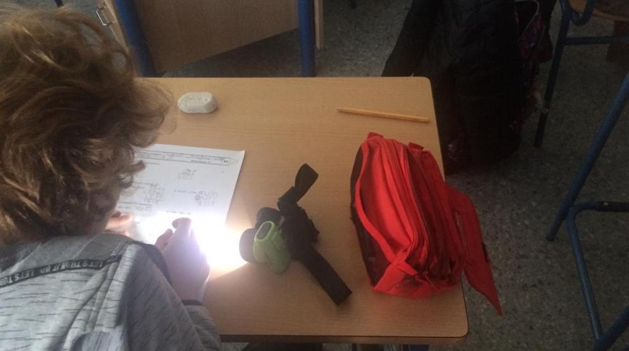 Un alumno del colegio Pedro Garfias de Sevilla, alumbrándose con una linterna