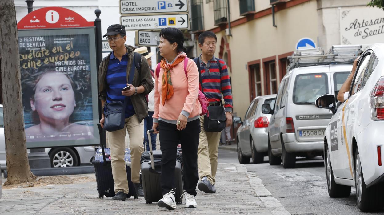 Varios turistas tiran de sus maletas por una de las calles de Sevilla
