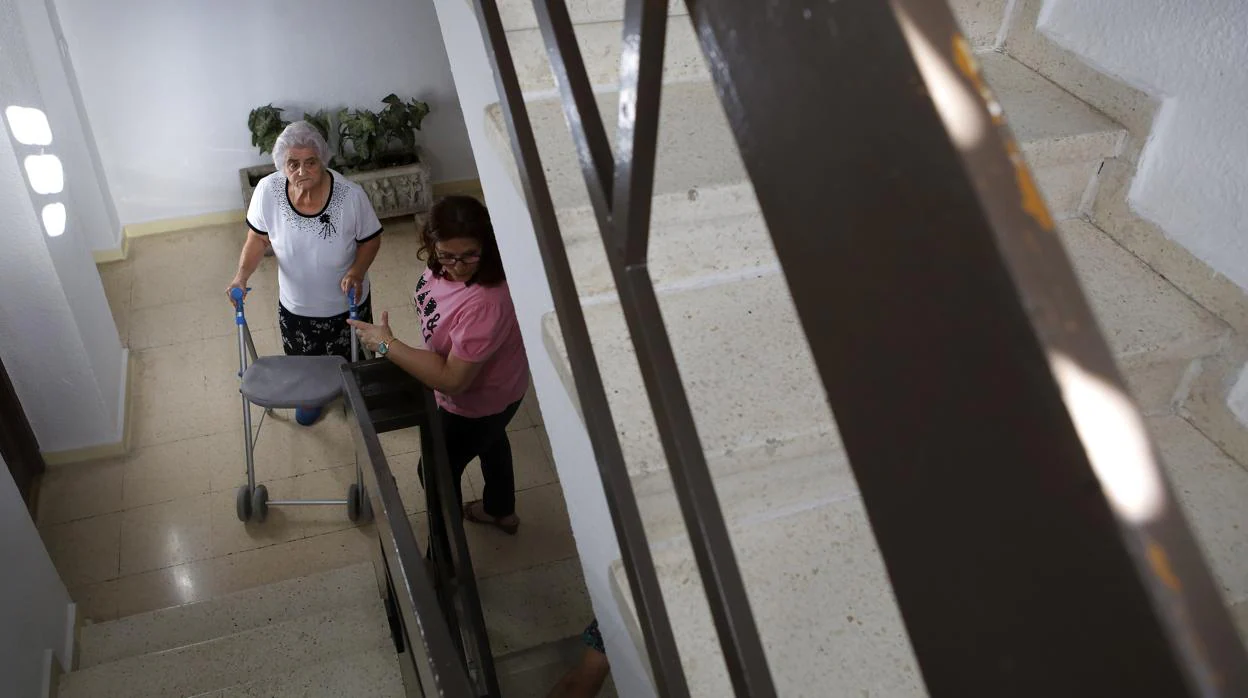 Una anciana con un andador sube las escaleras hacia su casa VALERIO MERINO