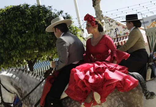 Un joven caballista junto a una mujer vestida de flamenca