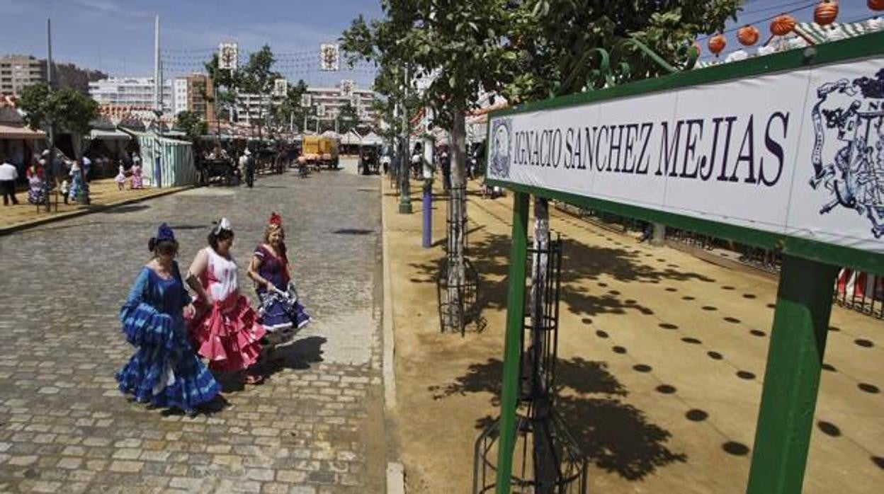 Mujeres vestidas de flamenca atraviesan la calle Sánchez Mejías