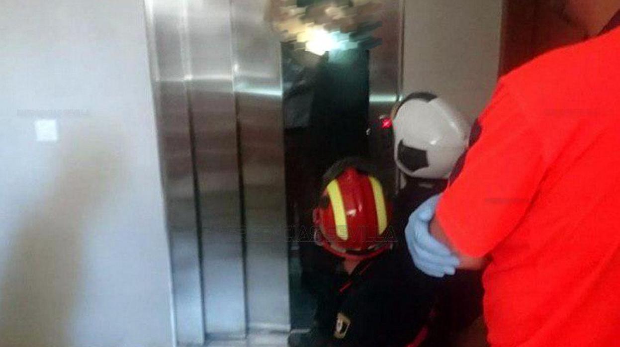 Los bomberos, en el momento en el que rescatan a la persona que cayó con el ascensor