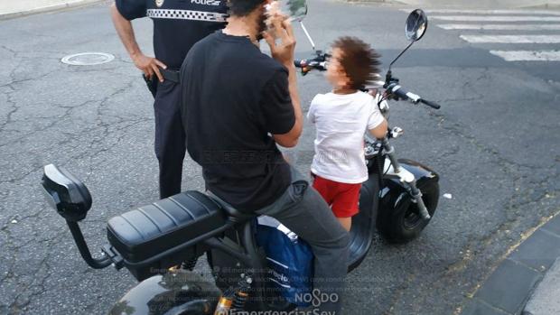 Circula por Sevilla entre los coches con un patinete eléctrico y un niño en el reposapiés