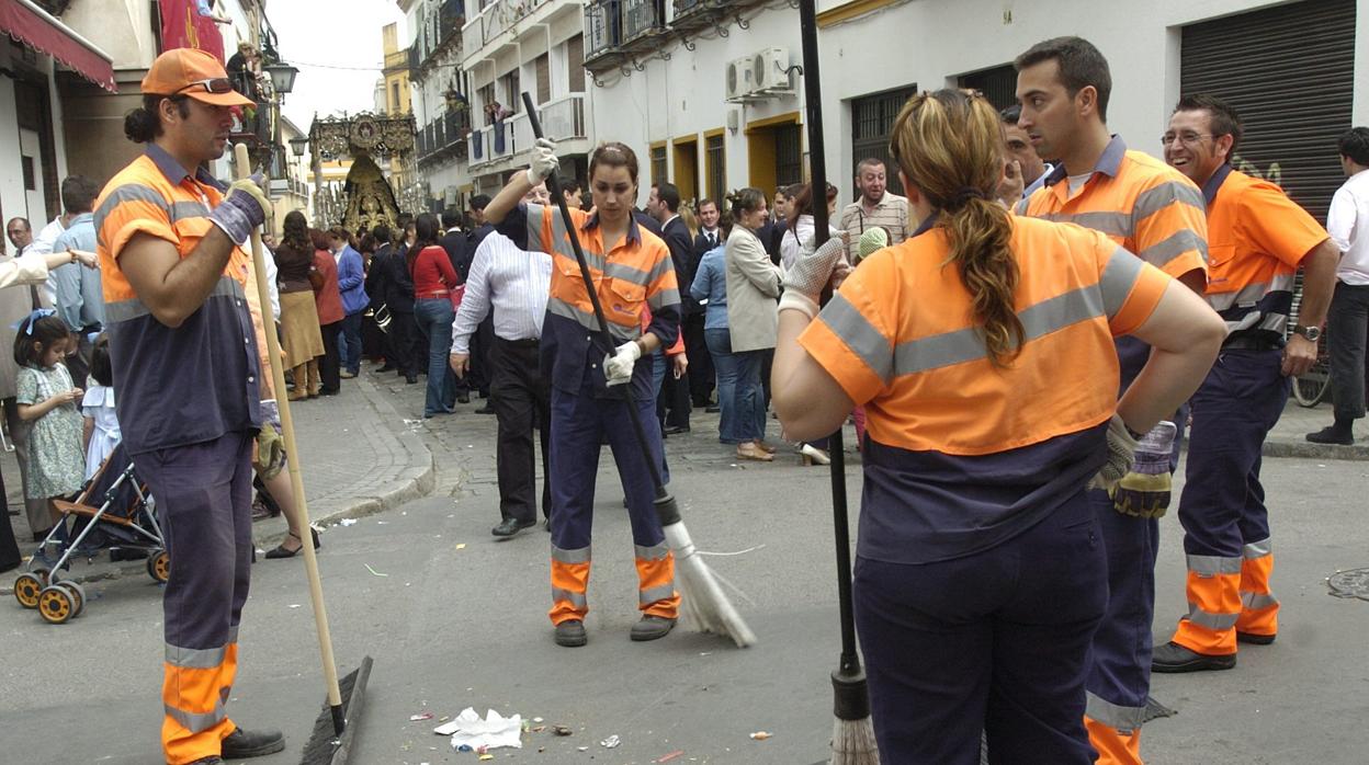 Varios operarios de Lipasam limpiando la calle tras pasar la hermandad del Buen Fin