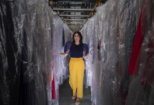 Carmen Osuna posa entre vestidos de su colección en el almacén donde los guarda