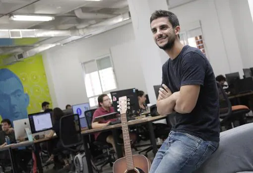 Héctor Giner posa junto a una guitarra, otra de sus pasiones, en la oficina de Z1 de Sevilla