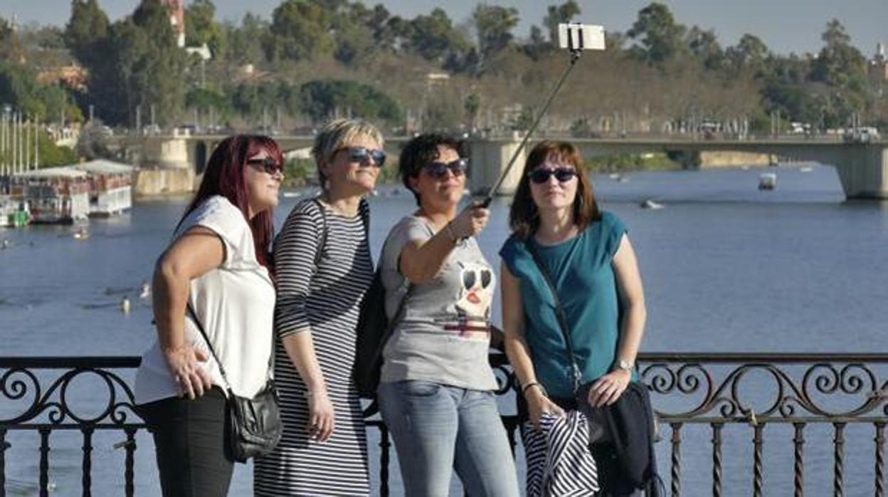 Unas turistas haciéndose una foto con el río Guadalquivir.