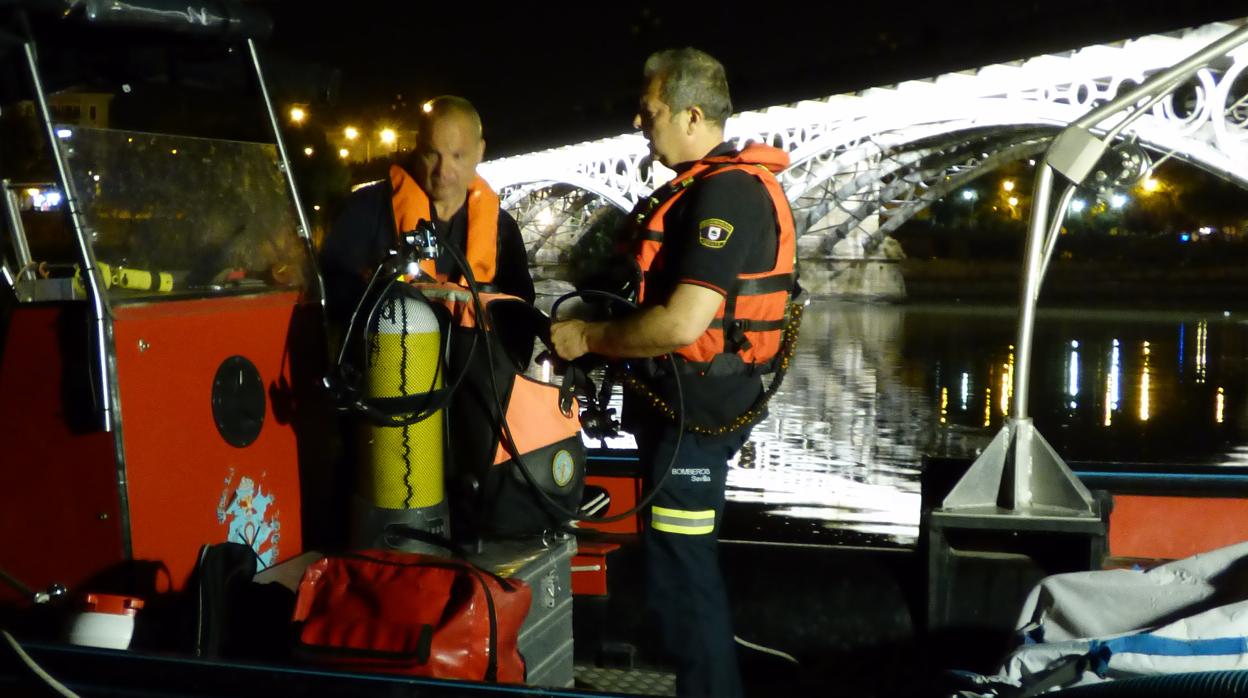 Mario Arcos, a la izquierda, trabajando junto al puente de Triana