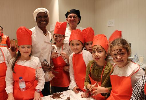 El chef Juan León con su ayudante Esther Richardson y un grupo de niñas participando en el taller de chocolate