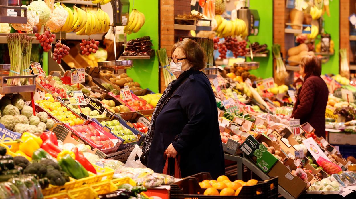 Una mujer comopra con mascarilla en una frutería