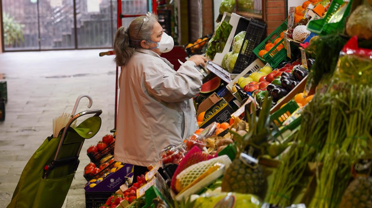 Una señora con mascarilla comprando en el mercado de Triana