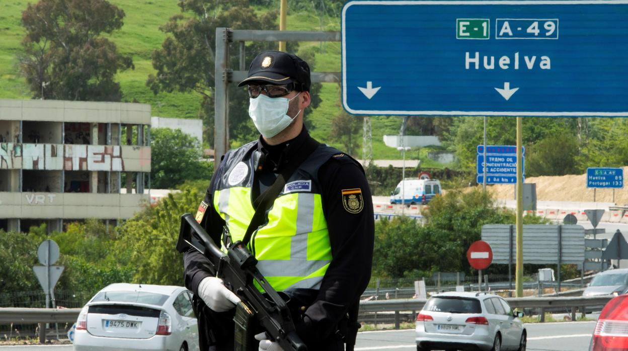 Un policía nacional controla la salida de coches hacia las playas desde Sevilla a Huelva