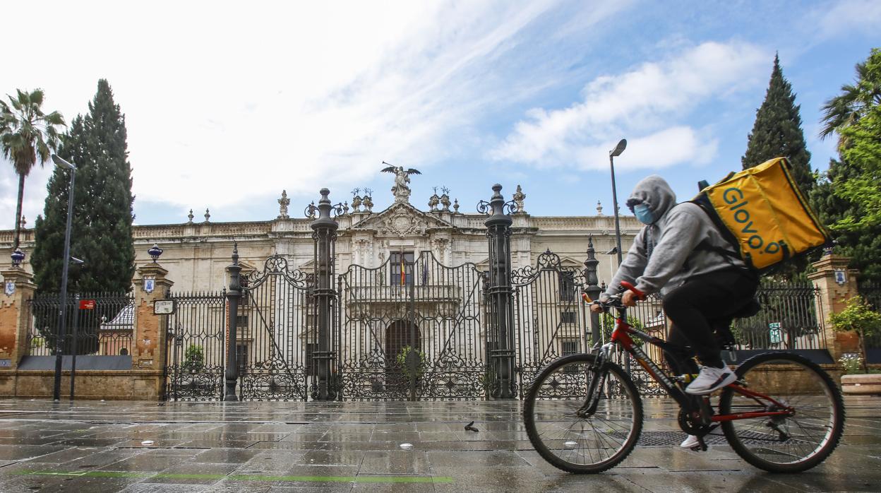 Un repartidor bajo la lluvia por la calle San Fernando, con la Universidad cerrada