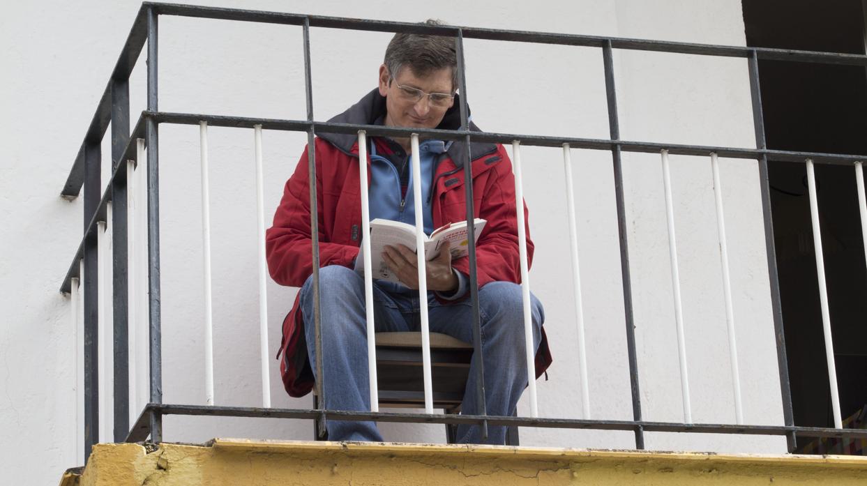 Un vecino de Sevilla lee plácidamente en su balcón