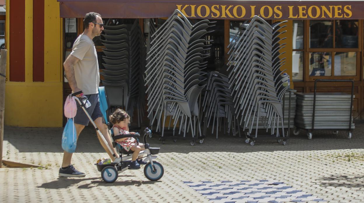 Un viandante pasea a un niño delante del Kiosco Los Leones, en la Alameda