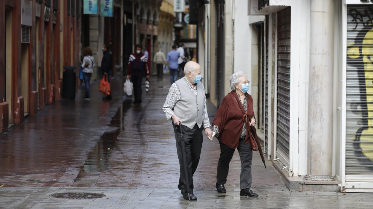 Dos personas mayores pasean por la calle Sagasta de Sevilla