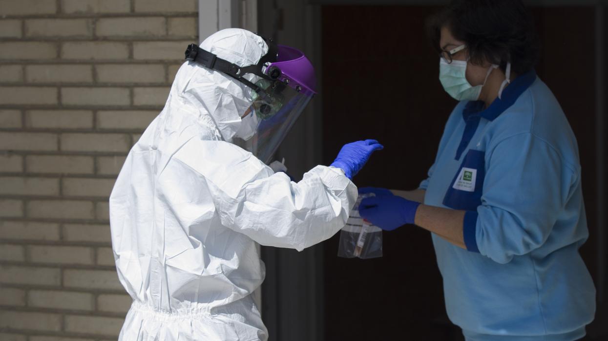 Un sanitario entrega las pruebas a otro, tras realizar una recogida de muestra desde el coche para detectar casos de coronavirus