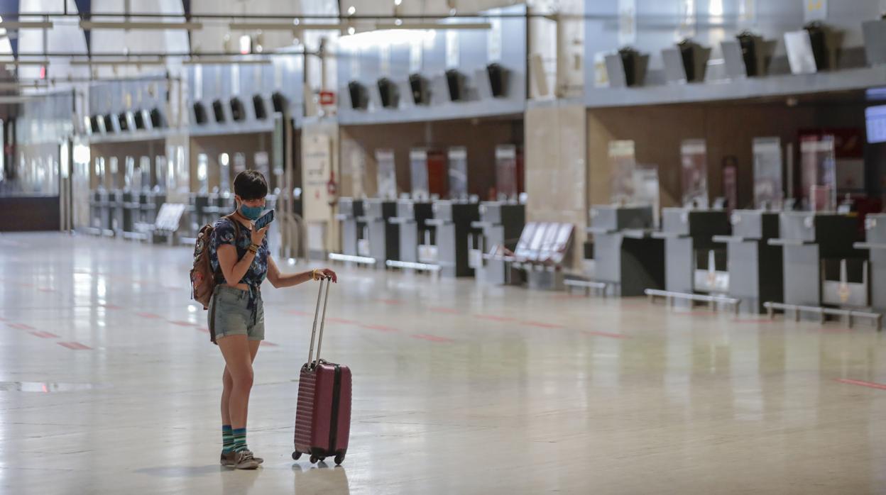 Una viajera consulta su móvil en el aeropuerto de Sevilla