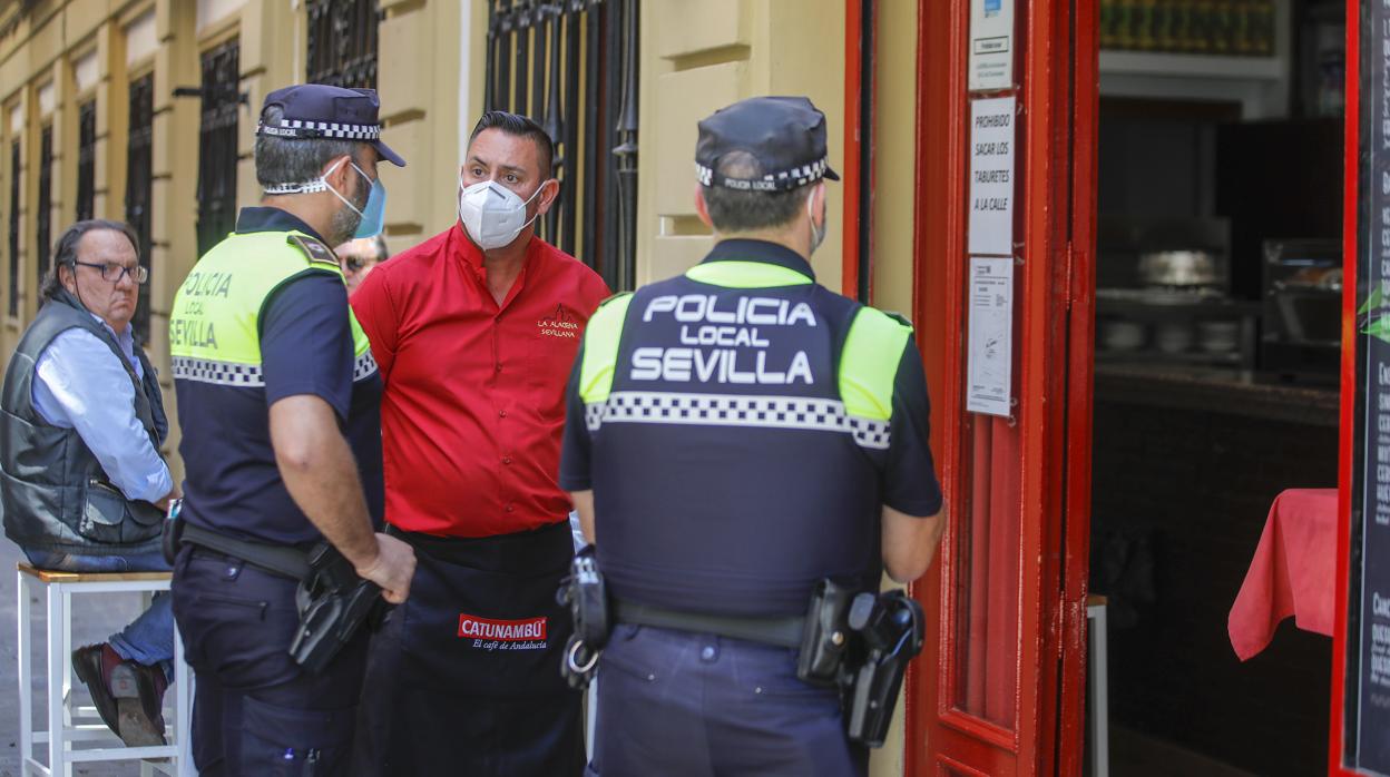 Dos agentes de la Policía Local de Sevilla revisan un bar céntrico