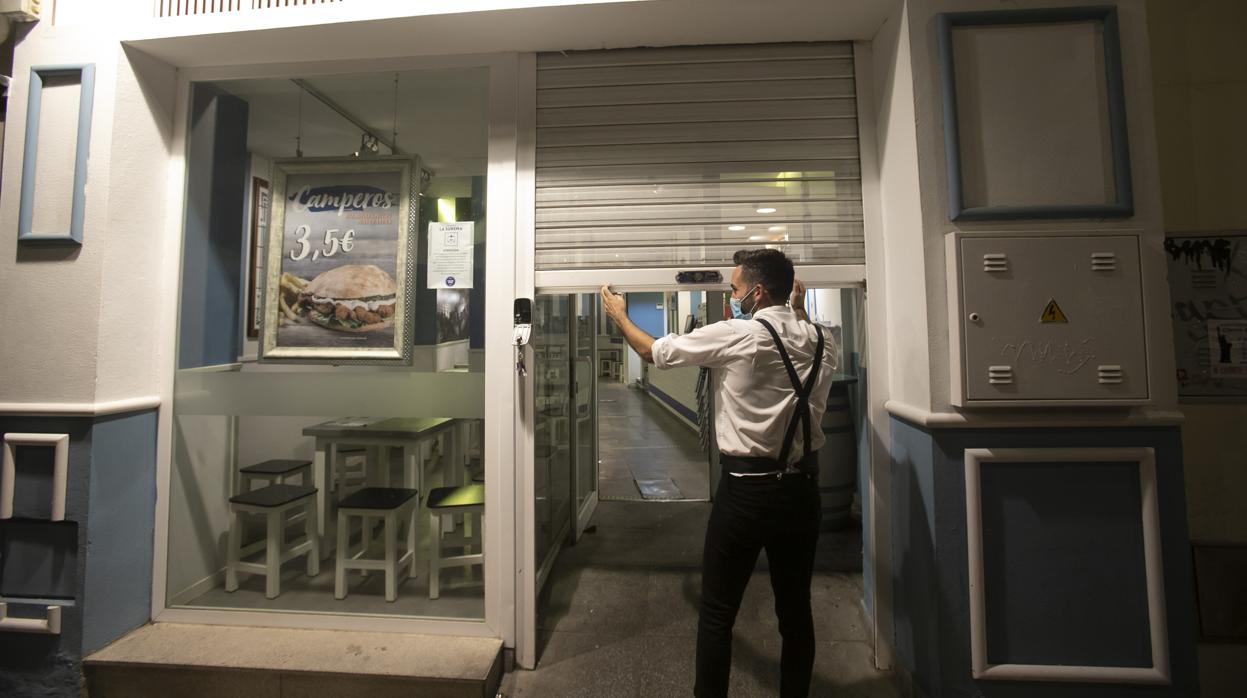 Un camarero cierra la persiana de un bar en Sevilla este domingo