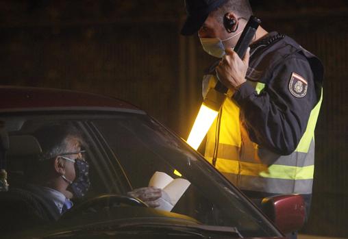 Un policía comprueba el salvoconducto del conductor para salir de Sevilla