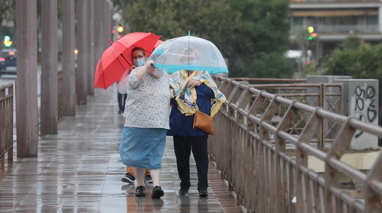 Dos señoras se guarecen de la lluvia en Sevilla