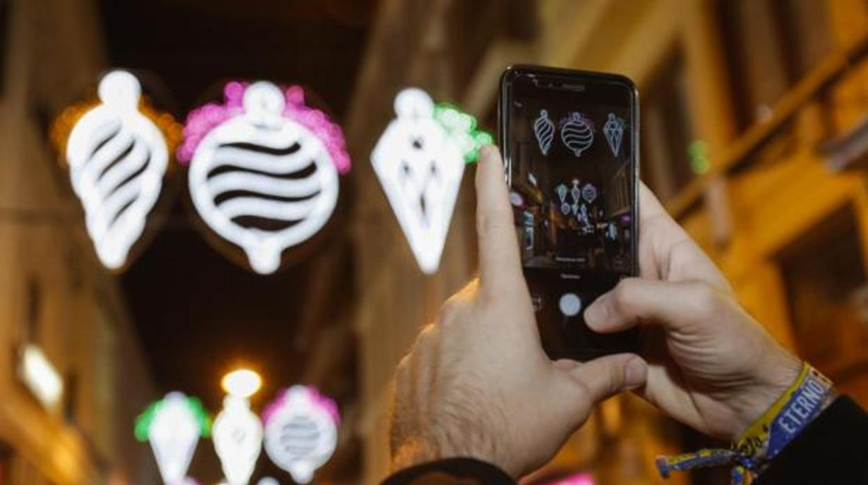 Un transeúnte hace una fotografía de la iluminación navideña